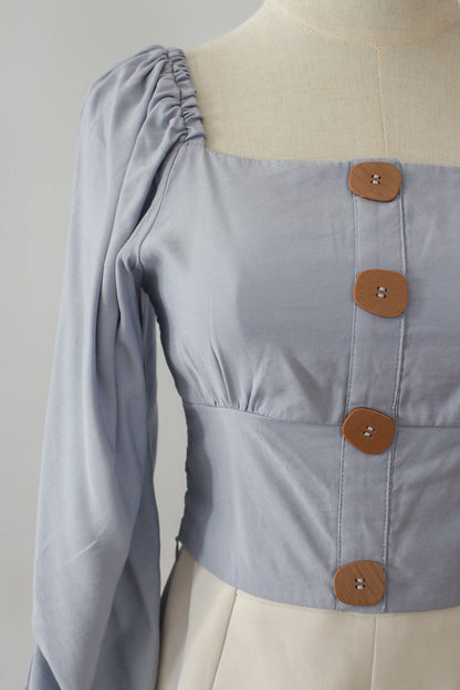 A square neck cropped top with long puffed sleeves. Complete with wooden finish buttons. 